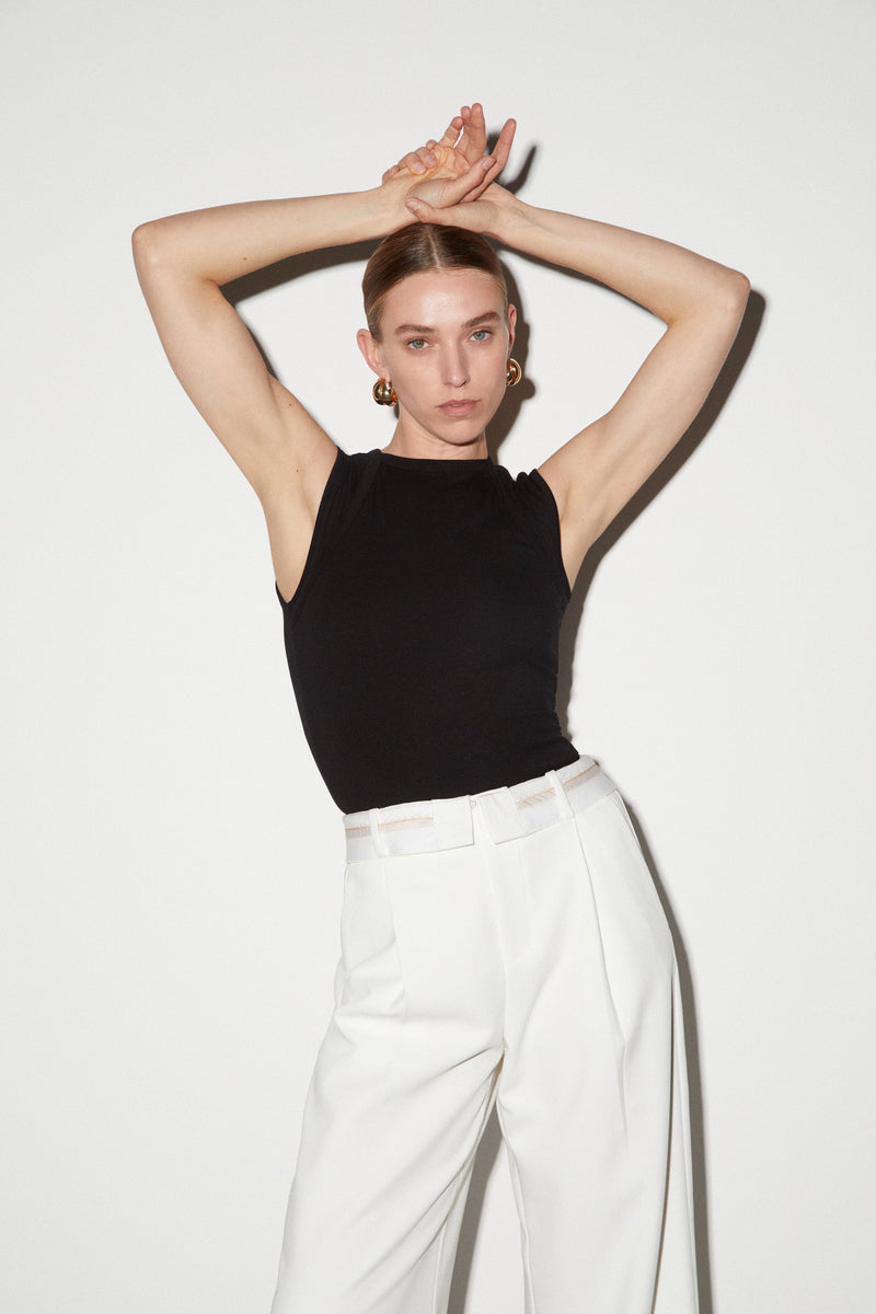 Girl wearing White long pants with white fold-over waistband and front pleats. Worn with black tank top.