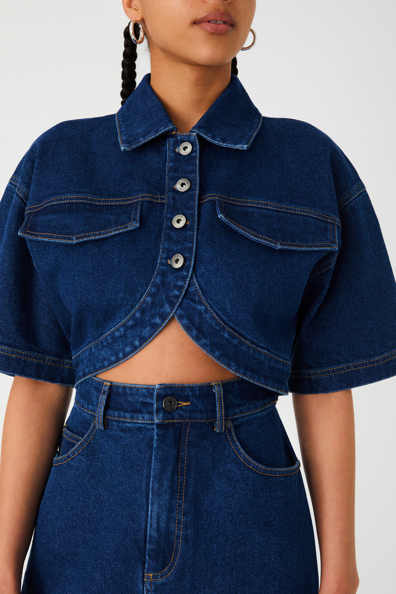 Denim dress with middle cutout. Dress features collar, buttons, oversized sleeves and curved hem