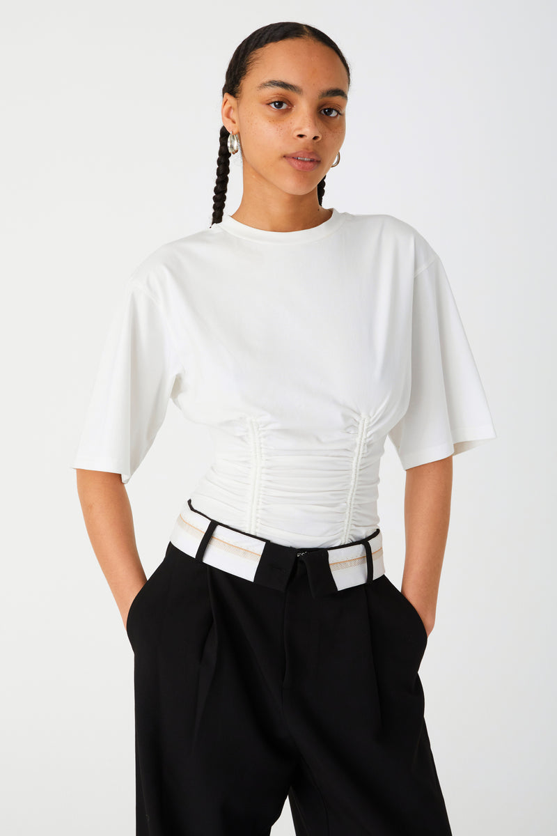 Girl wearing Black long pants with white fold-over waistband and front pleats. Worn with white tee-shirt with corset detailing.