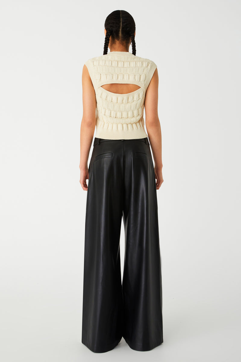 Woman wearing black wide-leg faux leather pants. Pants are oversized with large centre pleats.