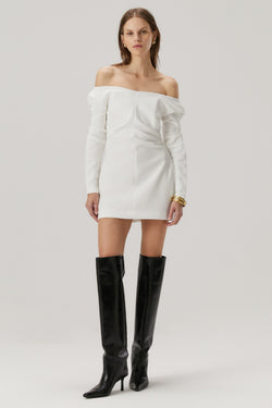 Girl with blonde hair wearing a bonded crepe dress in ivory. The dress features off the shoulder long sleeves