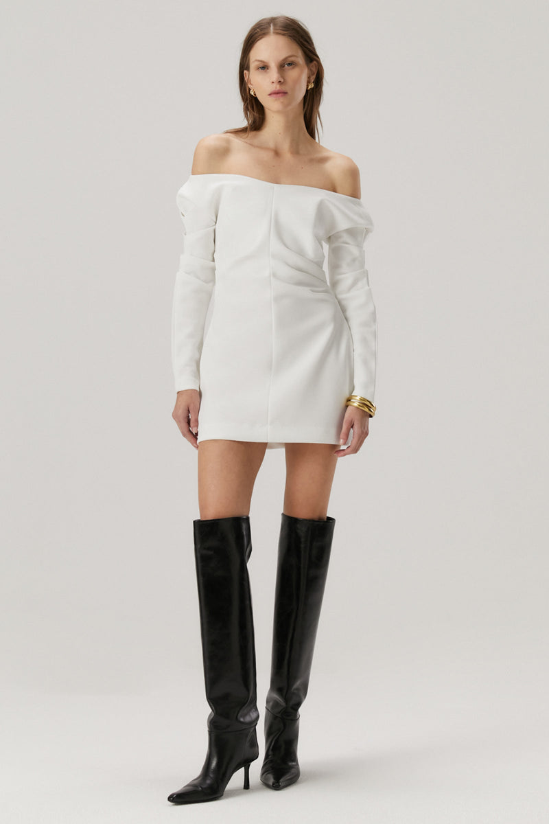 Girl with blonde hair wearing a bonded crepe dress in ivory. The dress features off the shoulder long sleeves
