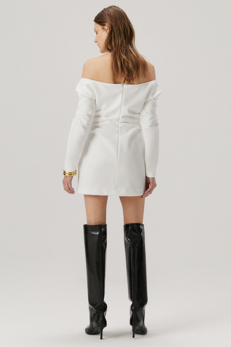 Girl with blonde hair wearing a bonded crepe dress in ivory. The dress features off the shoulder long sleeves