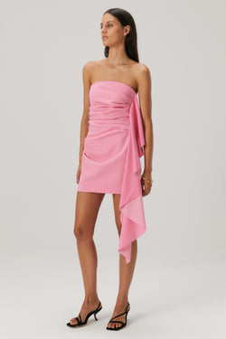 Lady in a pink bonded crepe mini dress with a satin flounce seam.