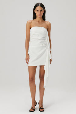 Lady in an ivory bonded crepe mini dress with a satin flounce seam.