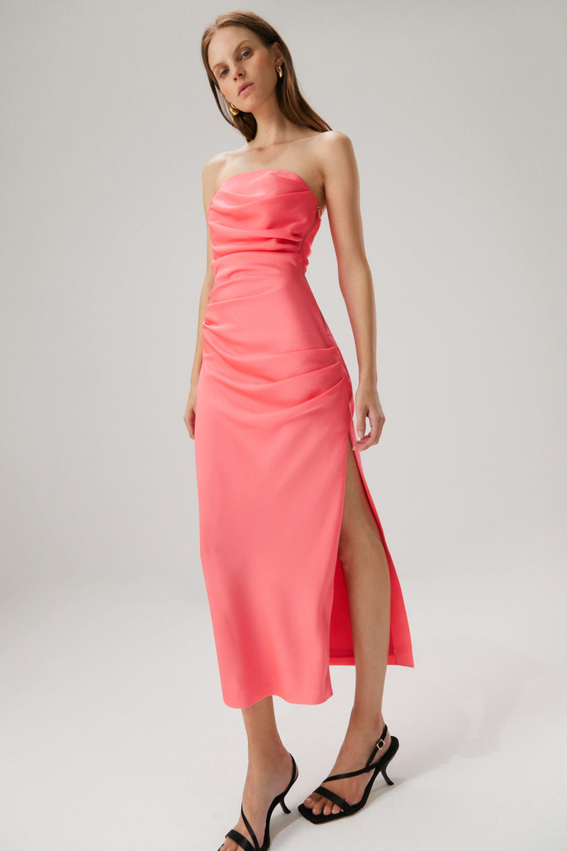 Girl with blonde hair wearing a pink strapless midi dress in a satin material. 
